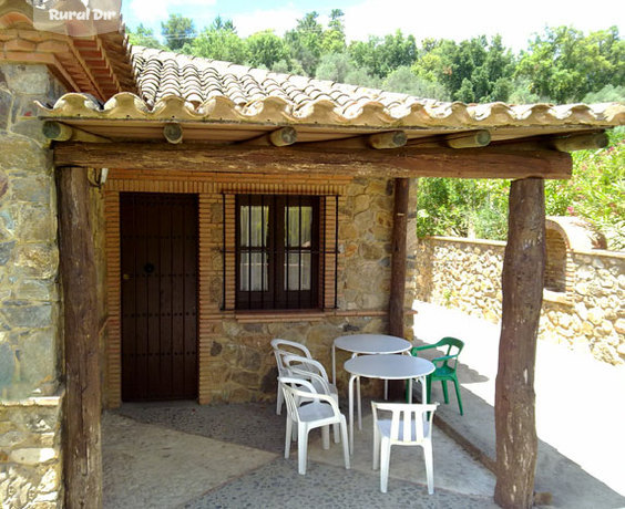 Porche cubierta fachada posterior con barbacoa de obra de la casa rural Casa de Piedra